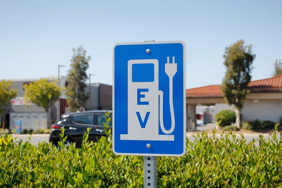 Blue sign with white gas pump symbol with electric plug and "EV"